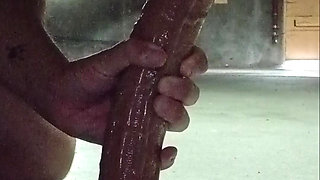 Sucks big naked dildo in an underground garage