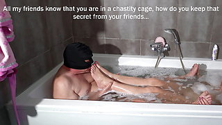 In the bath, my submissive in a chastity cage takes care of my feet