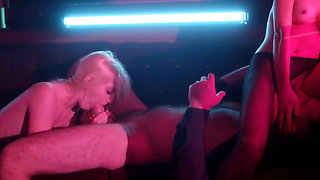 Two blondes take turns on a stud under neon lights
